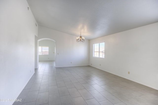 tiled empty room featuring an inviting chandelier