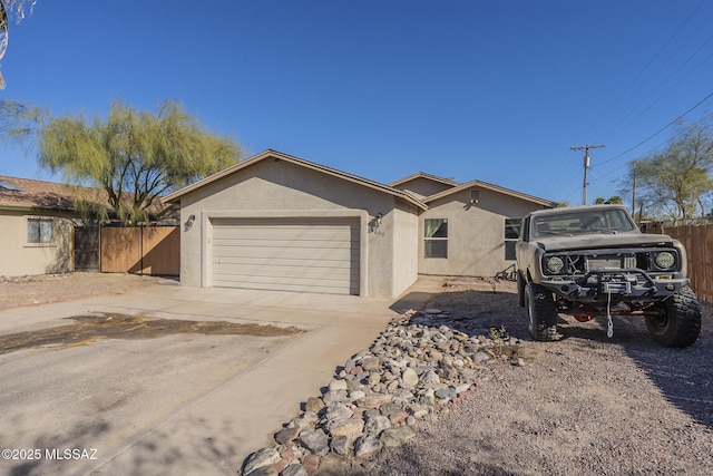 ranch-style house featuring a garage, concrete driveway, fence, and stucco siding