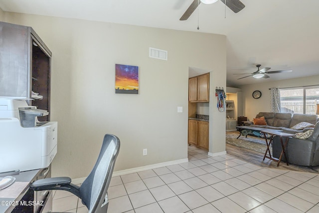 office space featuring lofted ceiling, visible vents, a ceiling fan, light tile patterned flooring, and baseboards