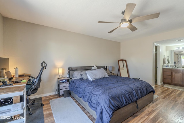 bedroom featuring ceiling fan, wood finished floors, visible vents, baseboards, and ensuite bath