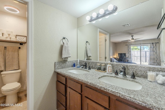 bathroom with double vanity, a sink, toilet, and connected bathroom