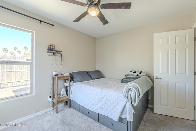 carpeted bedroom featuring ceiling fan, multiple windows, and baseboards