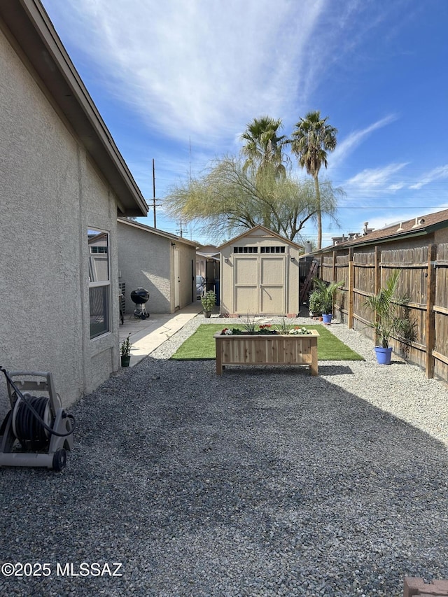 view of yard with an outbuilding, a patio area, a fenced backyard, and a storage shed