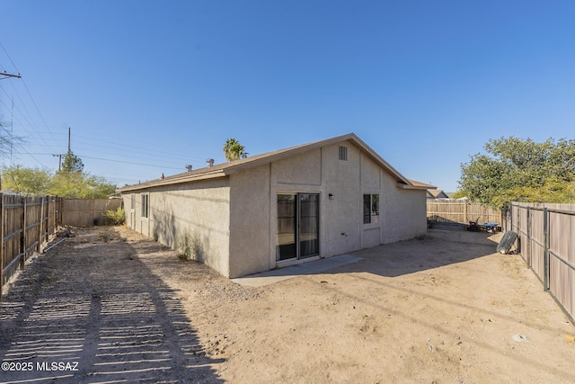 rear view of property featuring a fenced backyard and stucco siding