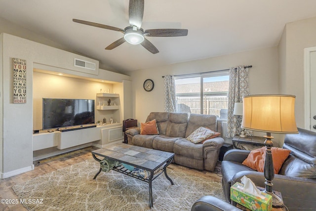 living area featuring lofted ceiling, baseboards, visible vents, and a ceiling fan