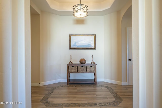 corridor with hardwood / wood-style flooring and a raised ceiling