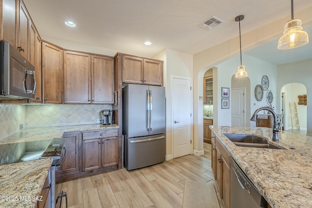 kitchen featuring pendant lighting, sink, light stone counters, and stainless steel appliances