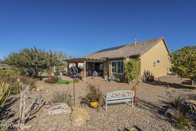 rear view of house featuring a patio and solar panels