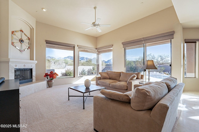 living room with a premium fireplace, a healthy amount of sunlight, a mountain view, and ceiling fan