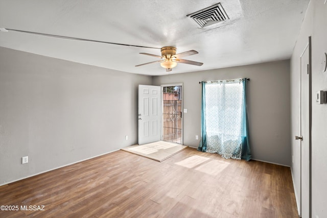 empty room with a textured ceiling, light hardwood / wood-style floors, and ceiling fan