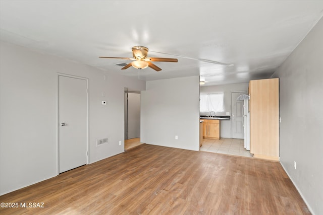 unfurnished living room featuring ceiling fan and light hardwood / wood-style floors