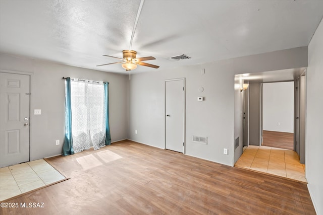 interior space featuring ceiling fan, a textured ceiling, and light wood-type flooring