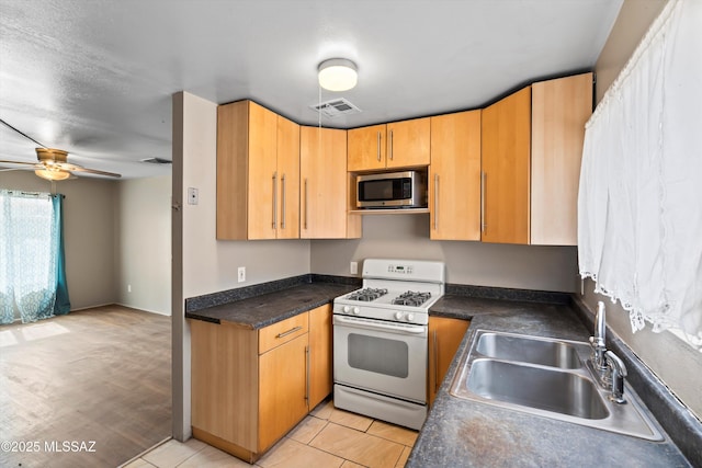 kitchen featuring sink, light tile patterned floors, white gas range oven, and ceiling fan