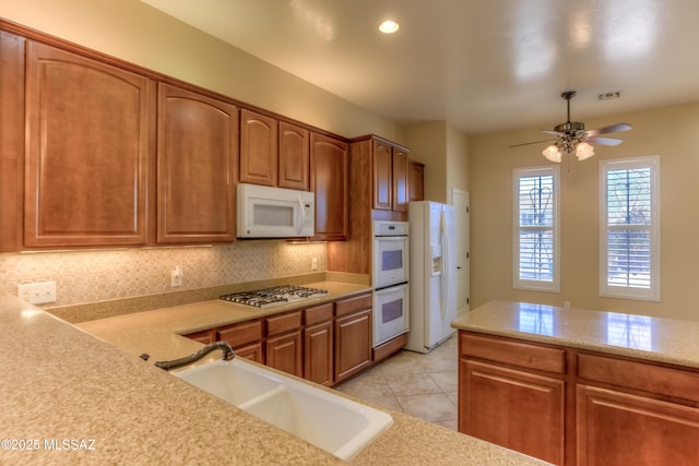 kitchen featuring white appliances, decorative backsplash, sink, ceiling fan, and light tile patterned floors