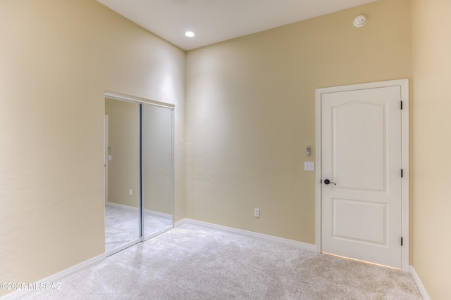 unfurnished bedroom featuring light carpet and a closet