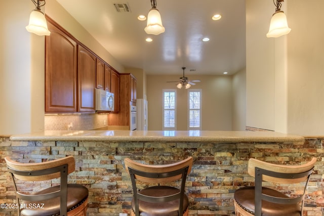 bar featuring decorative light fixtures, backsplash, white appliances, and ceiling fan