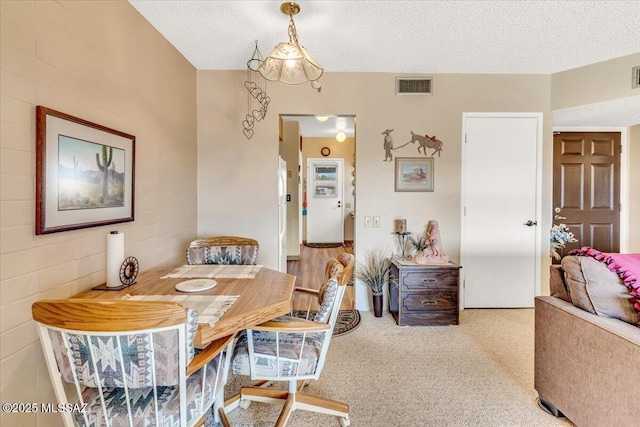 dining room featuring light colored carpet and a textured ceiling