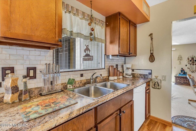 kitchen with sink, backsplash, hanging light fixtures, white dishwasher, and light wood-type flooring