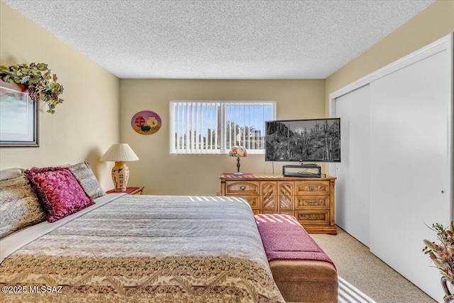 bedroom featuring light colored carpet, a textured ceiling, and a closet