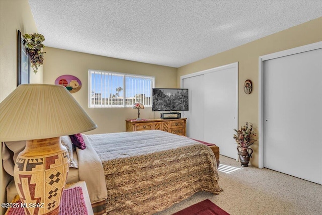 carpeted bedroom with multiple closets and a textured ceiling