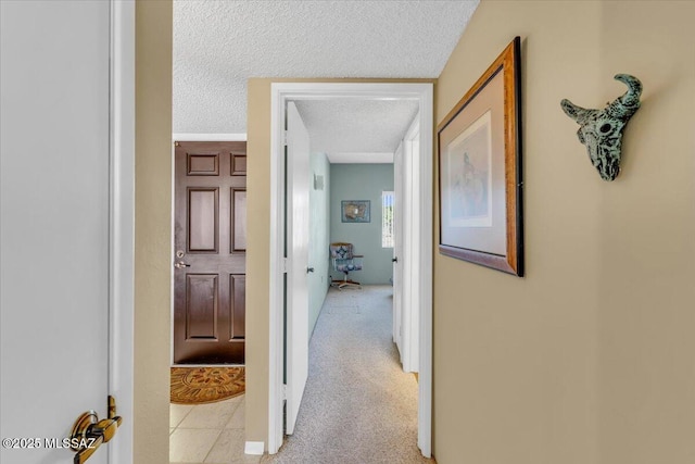 corridor featuring light colored carpet and a textured ceiling