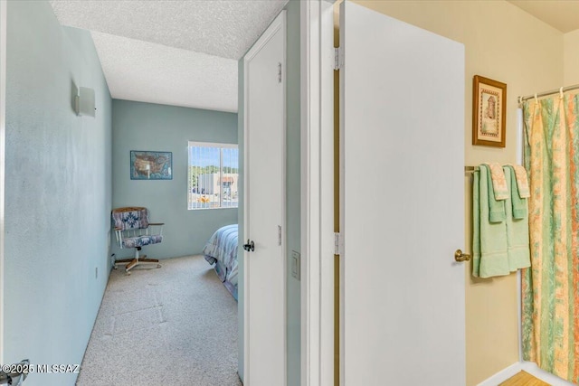 hall with light colored carpet and a textured ceiling