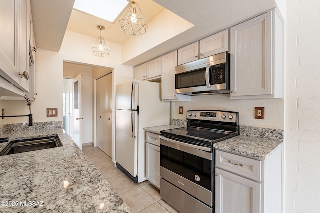 kitchen with pendant lighting, appliances with stainless steel finishes, white cabinets, light tile patterned floors, and light stone countertops