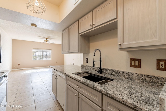 kitchen with dishwasher, sink, light tile patterned floors, light stone counters, and a textured ceiling