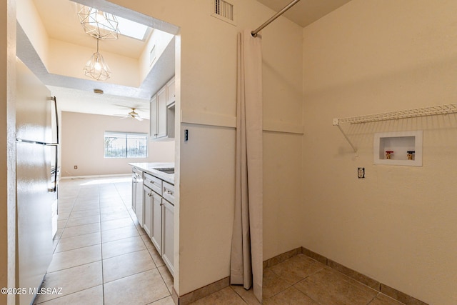 washroom with washer hookup, ceiling fan, a skylight, and light tile patterned flooring