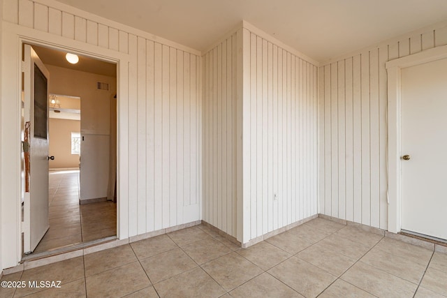 unfurnished room with wood walls and light tile patterned flooring