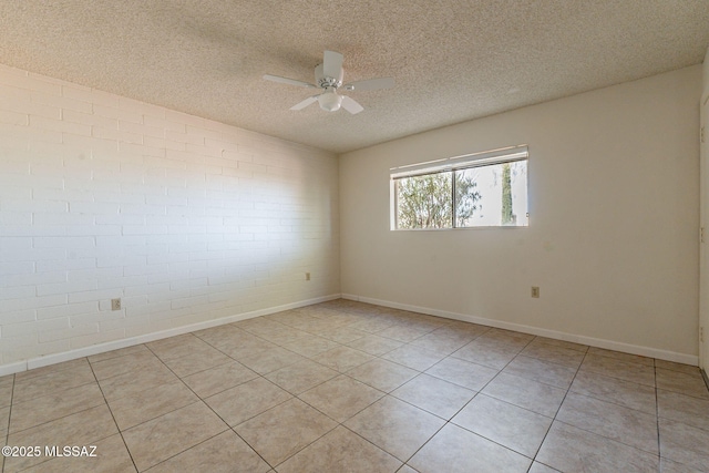 unfurnished room featuring ceiling fan, brick wall, a textured ceiling, and light tile patterned flooring