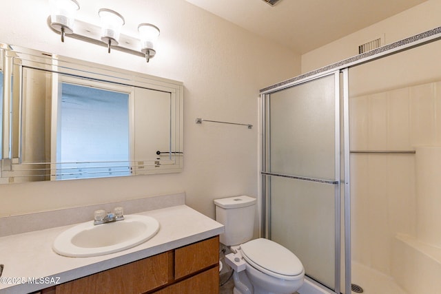 bathroom with vanity, toilet, and a shower with door