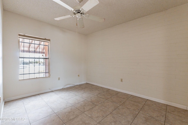 tiled empty room featuring ceiling fan, brick wall, and a textured ceiling