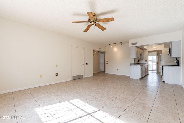 unfurnished living room featuring ceiling fan, a textured ceiling, and light tile patterned flooring