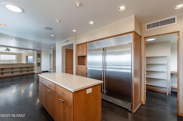 kitchen with dark hardwood / wood-style flooring, stainless steel built in fridge, and a kitchen island