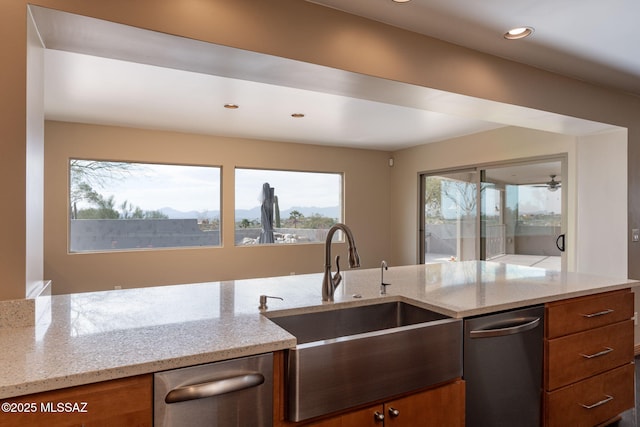 kitchen featuring light stone counters, dishwasher, and sink