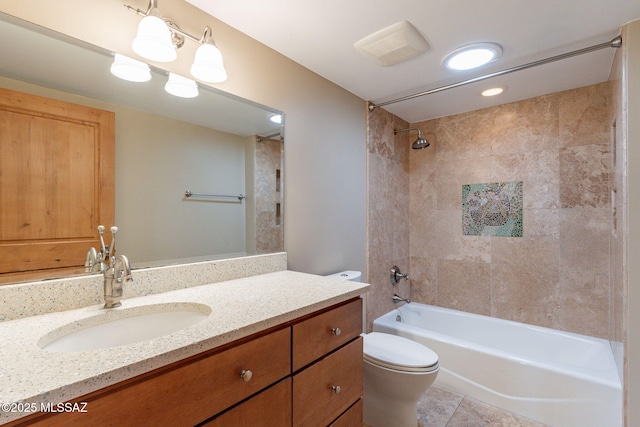 full bathroom with tile patterned flooring, tiled shower / bath, vanity, and toilet