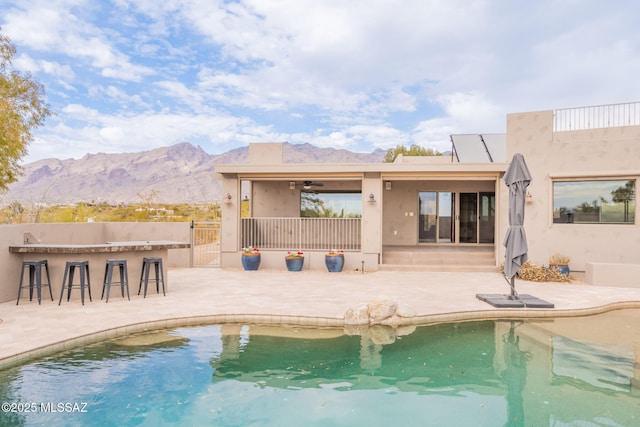 rear view of house featuring a mountain view, a patio area, ceiling fan, and a bar