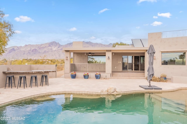 rear view of house featuring a mountain view, a patio, ceiling fan, and exterior bar