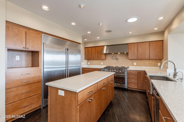 kitchen featuring high quality appliances, sink, backsplash, dark hardwood / wood-style flooring, and wall chimney exhaust hood