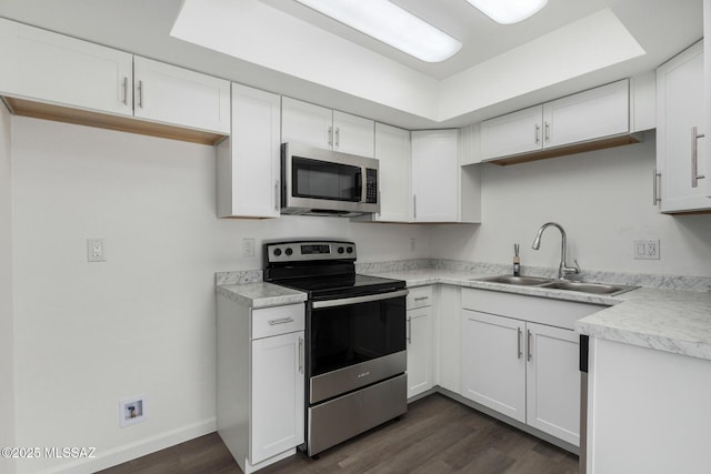 kitchen with dark wood-type flooring, appliances with stainless steel finishes, sink, and white cabinets