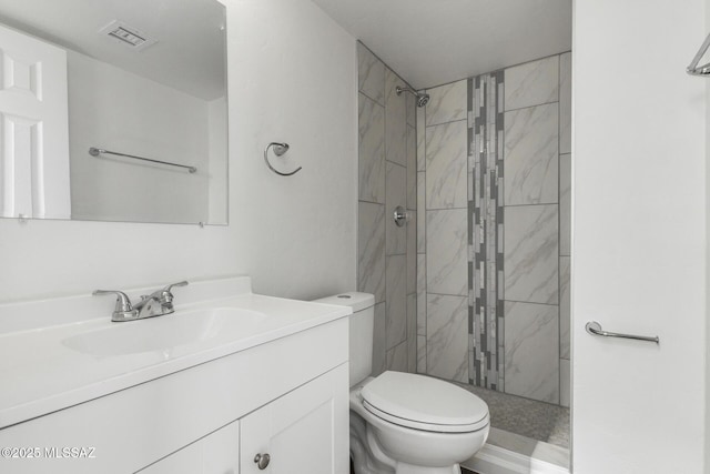 bathroom featuring vanity, toilet, and a tile shower