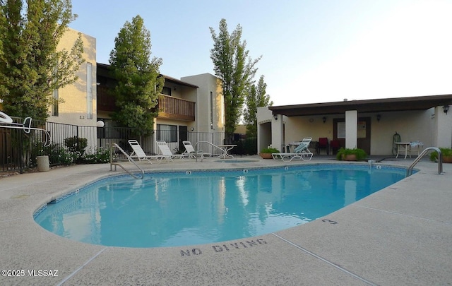 pool with a patio area and fence