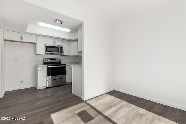 kitchen with stainless steel appliances, white cabinetry, and dark wood-type flooring