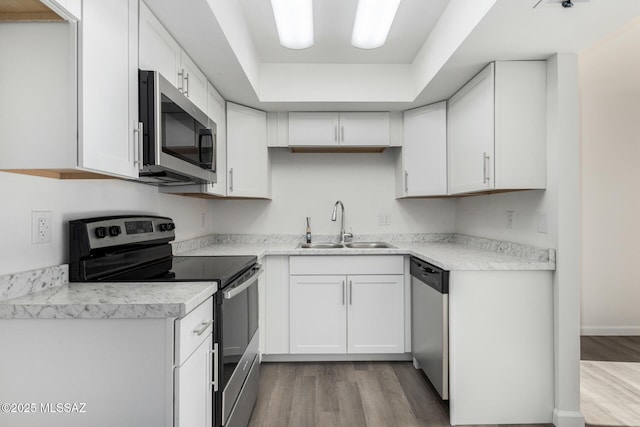 kitchen with sink, light hardwood / wood-style flooring, white cabinets, and appliances with stainless steel finishes