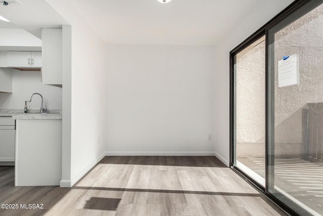 unfurnished dining area featuring wood finished floors, a healthy amount of sunlight, and baseboards