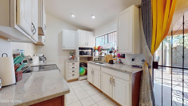 kitchen featuring vaulted ceiling, sink, white cabinets, and light tile patterned flooring