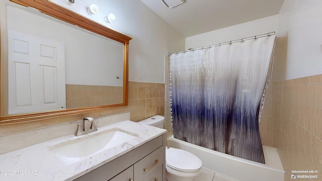 full bathroom with toilet, tile walls, vanity, and shower / bath combo with shower curtain