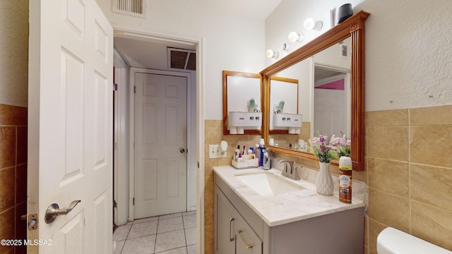 bathroom featuring toilet, vanity, tile walls, and tile patterned floors