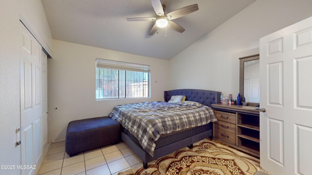 bedroom featuring ceiling fan, light tile patterned floors, a closet, and lofted ceiling